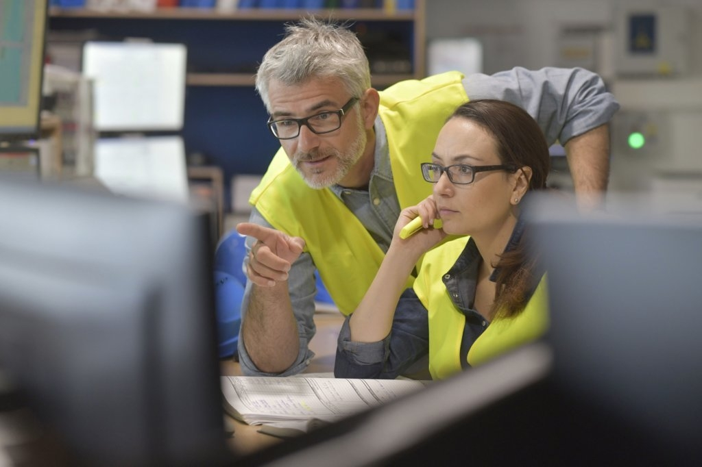 Two people looking at a computer screen - One is pointing at the screen
