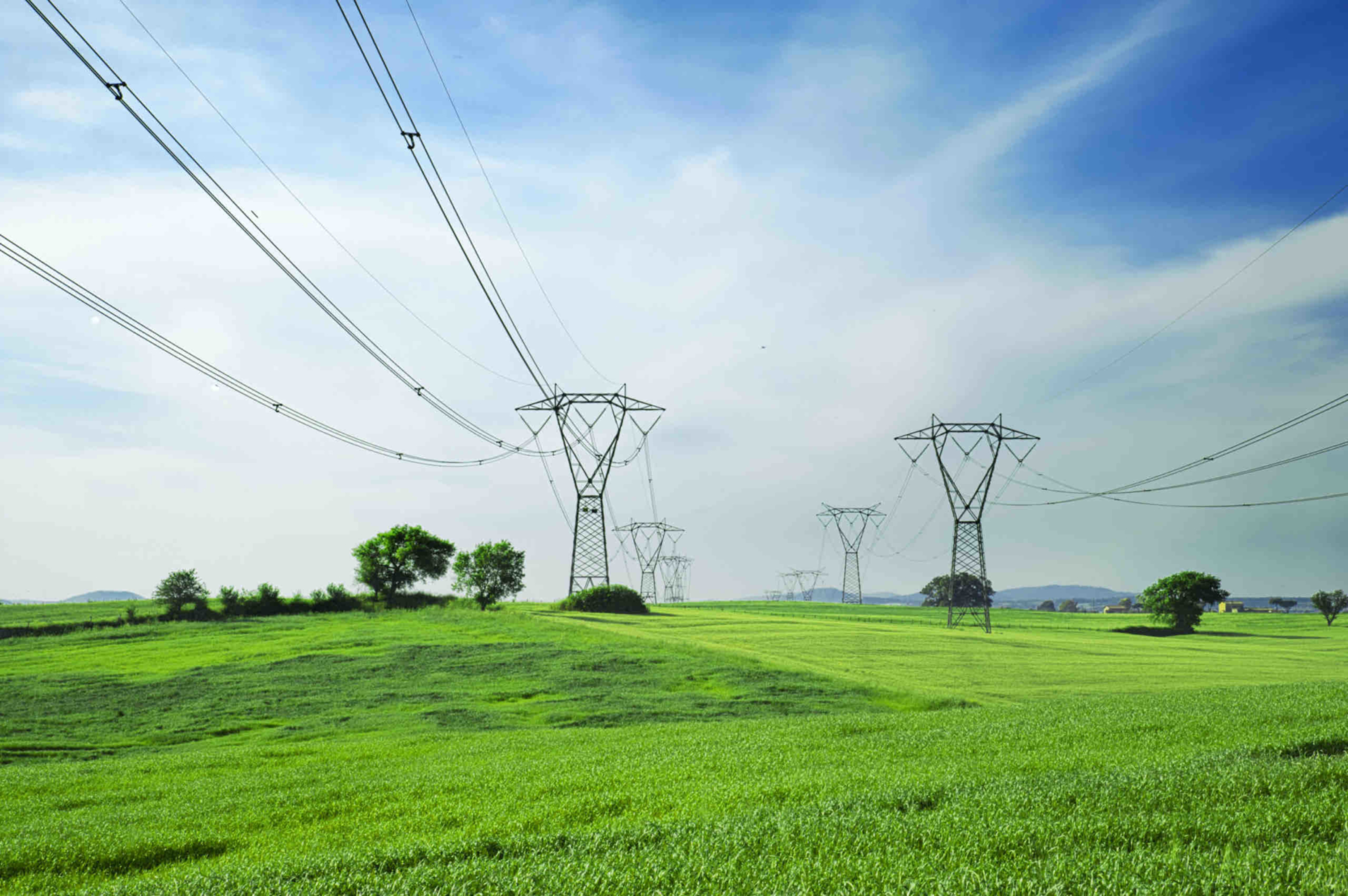 Power Transmission and Distribution - Pylons with green grass and blue sky